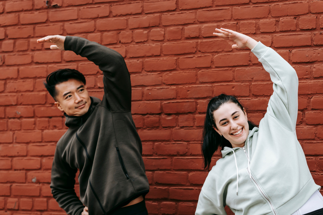 Happy multiethnic friends stretching body before workout on street